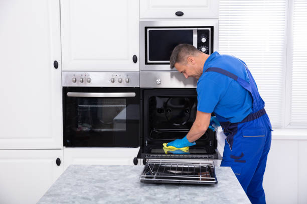 istockphoto-1096969784-612×612 Close-up Of A Smiling Male Janitor Cleaning Oven With Yellow Napkin In The Kitchen